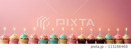 Colorful cupcakes with lit candles are displayed against a pink background, indicating an indoor celebration event marking of joy and celebrating. with free space Colorful cupcakes with lit candles are displayed against a pink background, indicating an indoor celebration event marking of joy and celebrating. with free space 113286468