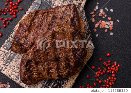 Fresh juicy delicious beef steak on a dark background Fresh juicy delicious beef steak on a dark background 113286520