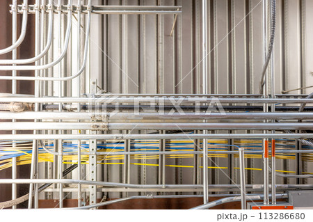 Looking up into an industrial ceiling with complex crisscross of utilities. Looking up into an industrial ceiling with complex crisscross of utilities. 113286680