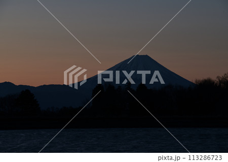 南東の空が朱に染まり始める夜明け前、風で水面は細波たち明け行く富士 113286723