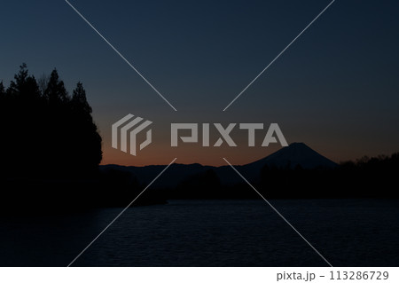 南東の空が朱に染まり始める夜明け前、風で水面は細波たち明け行く富士 113286729