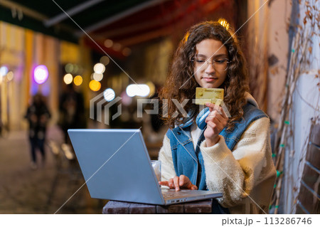 Girl using credit bank card laptop transferring money drinking coffee purchases online shopping Girl using credit bank card laptop transferring money drinking coffee purchases online shopping 113286746