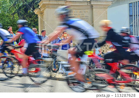 Abstract arty background: motion blur of bicycle racers competing on city streets. Tour of cycling. Blurry background sport with cyclists Abstract arty background: motion blur of bicycle racers competing on city streets. Tour of cycling. Blurry background sport with cyclists 113287628