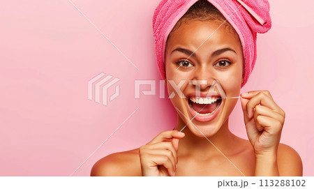 A young woman with bright pink towel on her head happily practices oral hygiene, cleans her gums and teeth with dental floss. The concept of taking care of your health, preventing dental diseases A young woman with bright pink towel on her head happily practices oral hygiene, cleans her gums and teeth with dental floss. The concept of taking care of your health, preventing dental diseases 113288102