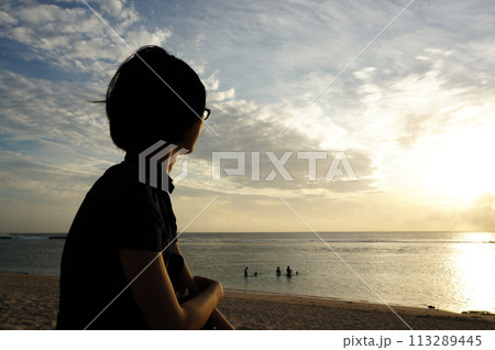 夕日を眺める女性の後ろ姿 113289445