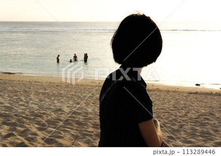 夕日を眺める女性の後ろ姿 113289446