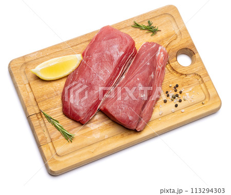 Fresh tuna Fish steak on a wooden cutting serving board isolated on a white background 113294303