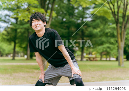 公園で運動前の準備運動・ウォーミングアップで膝屈伸するスポーツウェアの男性 113294908
