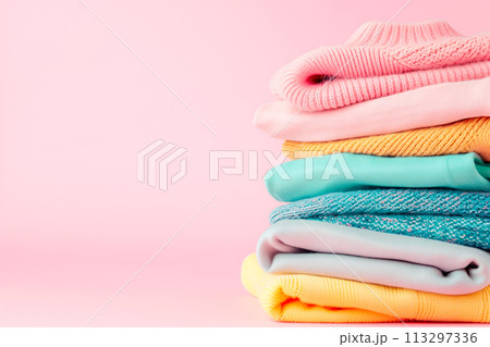 Pile of knitted sweaters and cozy scarves on pink background with copy space, Stack of clothes 113297336