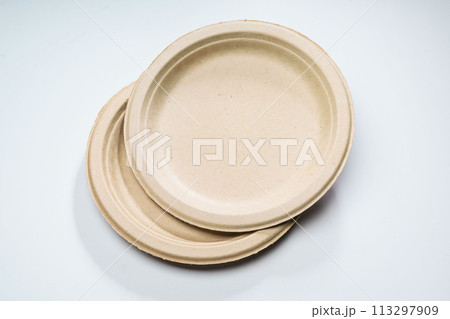 Disposable paper plates made of vegetable raw materials in beige color lie on the table. 113297909