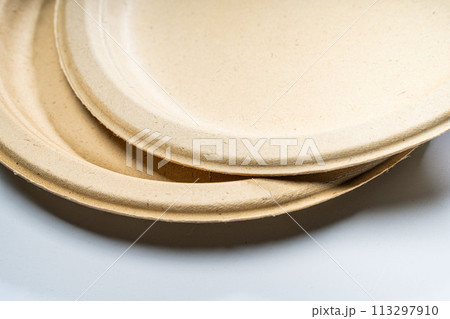 Disposable paper plates made of vegetable raw materials in beige color lie on the table. 113297910