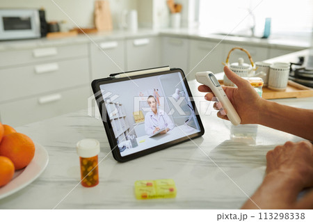 Man measuring temperature when talking to doctor using telemedicine service Man measuring temperature when talking to doctor using telemedicine service 113298338