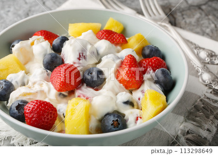 Summer cheesecake salad with strawberries, blueberries, pineapple, dressed with cream cheese and cream close-up in a bowl. Horizontal Summer cheesecake salad with strawberries, blueberries, pineapple, dressed with cream cheese and cream close-up in a bowl. Horizontal 113298649