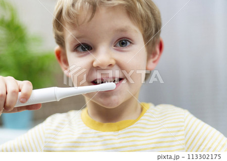 Young boy brushing teeth with electric toothbrush. 113302175
