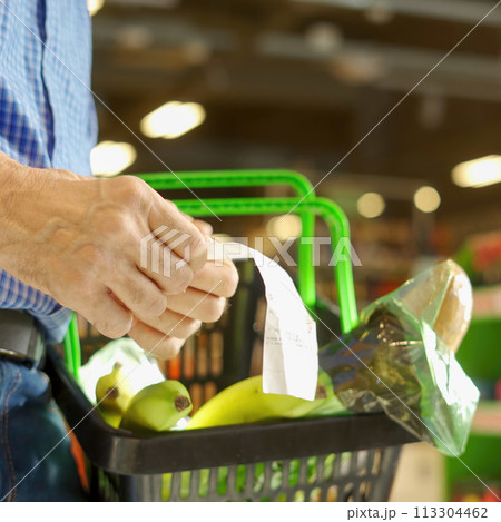 A grocery check in the hands of an elderly man A grocery check in the hands of an elderly man 113304462