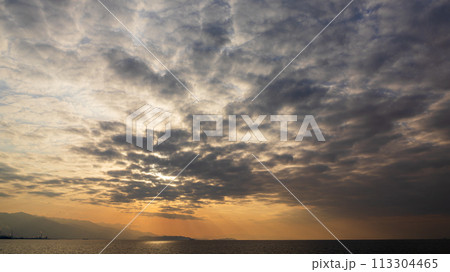 夕方の空に沈んでいく夕陽と、たくさんの雲 113304465