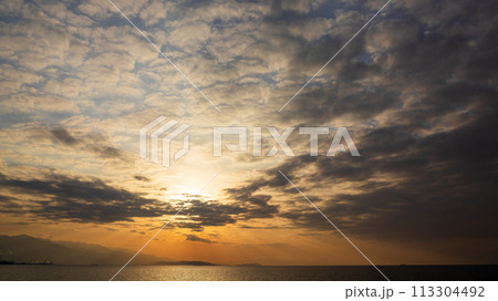 夕方の空に沈んでいく夕陽と、たくさんの雲 113304492