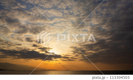 夕方の空に沈んでいく夕陽と、たくさんの雲 夕方の空に沈んでいく夕陽と、たくさんの雲 113304503