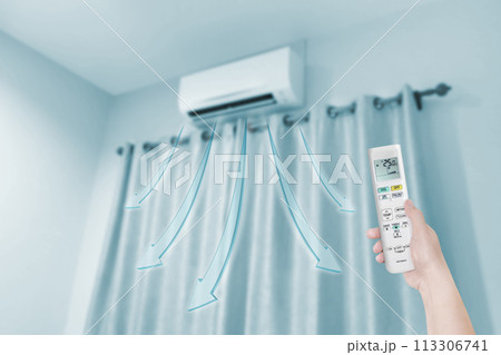 woman holding air conditioner remote control with air conditione woman holding air conditioner remote control with air conditione 113306741