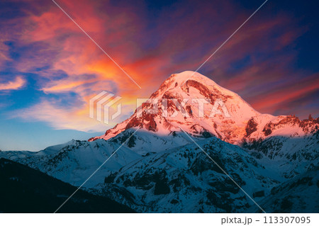 Georgia. Mount Kazbek Covered Snow In Winter Sunrise. Morning Dawn Colored Top Of Mountain In Pink-orange Colors. Awesome Winter Georgian Nature Landscape. 113307095