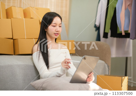Successful businesswoman has fun selling online and delivering packages in her home office Woman checking orders on notebook and laptop, SME business concept 113307500