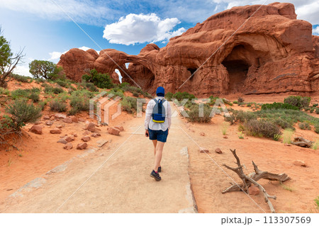 Woman Hiking to Double Arch in Utah National Park Woman Hiking to Double Arch in Utah National Park 113307569