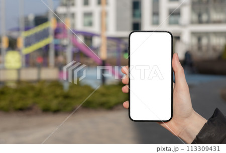 Hand holding mobile phone screen, blank smartphone display mockup, blurred city 113309431