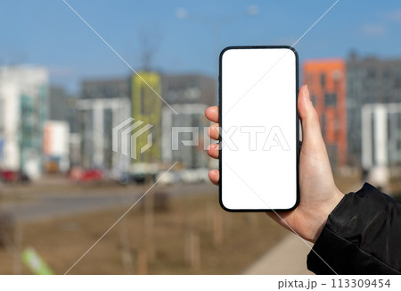Hand holding mobile phone screen mockup, empty blank smartphone frame, city buildings 113309454