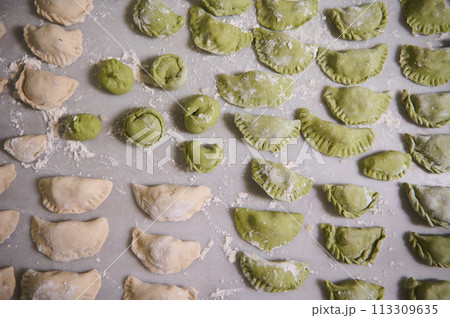 Food background with molded raw dumplings. Varennyky and ravioli on a floured marble surface of kitchen table. Ukrainian traditional cuisine. Food. Traditions and culture 113309635