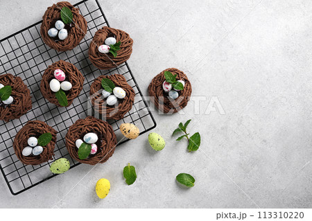 Easter chocolate cookies. Nests with sweet eggs on white background with mint leaves Easter chocolate cookies. Nests with sweet eggs on white background with mint leaves 113310220