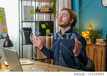 Peaceful relaxed businessman sitting at workplace with folded in mudra gesture hands meditating Peaceful relaxed businessman sitting at workplace with folded in mudra gesture hands meditating 113310691