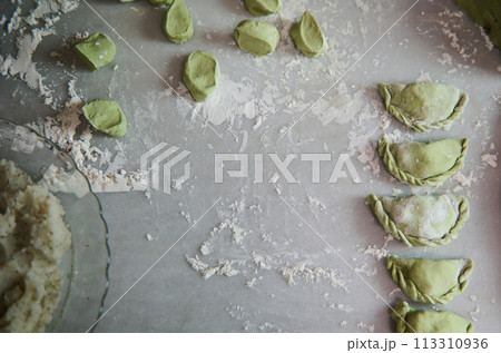 Top view. Food background with molded raw dumplings, Ukrainian Varennyky and Italian ravioli on a floured marble surface of kitchen table. Traditional cuisine. Food background. Copy advertising space 113310936