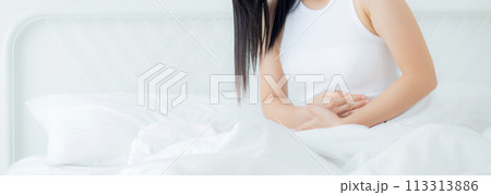 Young asian woman sitting on bed pain stomach or bowel with disease constipation. Young asian woman sitting on bed pain stomach or bowel with disease constipation. 113313886