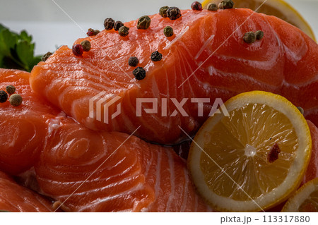 Fresh raw salmon fillet with cooking ingredients, herbs and lemon on black slate Fresh raw salmon fillet with cooking ingredients, herbs and lemon on black slate 113317880