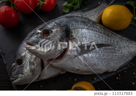 Sea bream or dorado sea fish herbs on dark slate background Top view  113317883