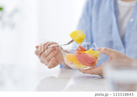水のグラスを手にフルーツを食べるミドル女性の手元 水のグラスを手にフルーツを食べるミドル女性の手元 113318643