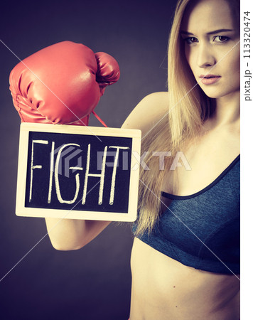 Woman wearing boxing glove holding fight sign 113320474