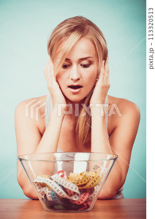 Diet. Girl with colorful measuring tapes in bowl 113320513