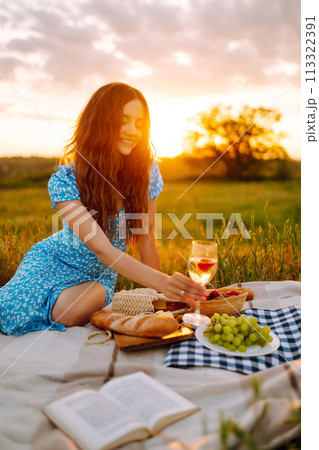 Young woman sits on a plaid with a book. Summer picnic in nature. Healthy food. Young woman sits on a plaid with a book. Summer picnic in nature. Healthy food. 113322391