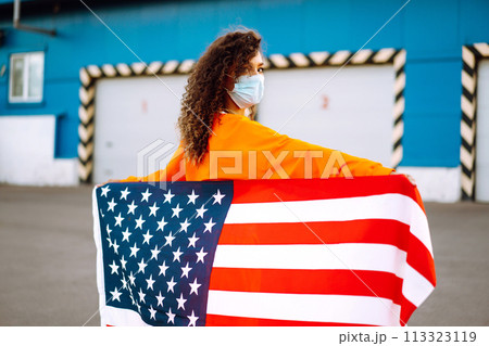 African American woman with medical face mask posing with american flag.The concept of preventing the spread of the epidemic. Covid-2019. African American woman with medical face mask posing with american flag.The concept of preventing the spread of the epidemic. Covid-2019. 113323119