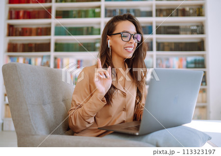 Young woman with wireless headphones calling on laptop. Online conference. Freelancer concept. 113323197