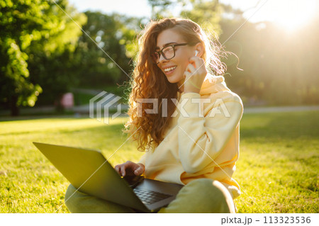 Smiling young woman with laptop working on background of city building. Education, freelance concept Smiling young woman with laptop working on background of city building. Education, freelance concept 113323536