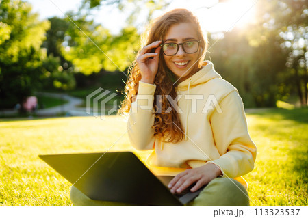 Smiling young woman with laptop working on background of city building. Education, freelance concept Smiling young woman with laptop working on background of city building. Education, freelance concept 113323537