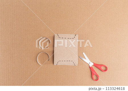 Scissors are positioned atop a cardboard-cut paper.  113324618