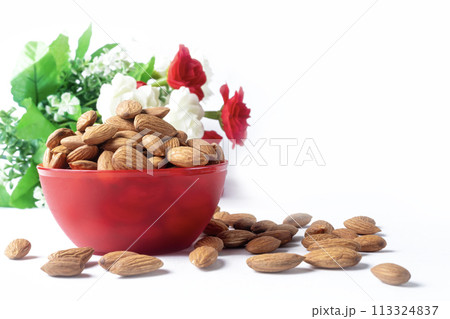 Almonds in red bowl on white background with copy space 113324837