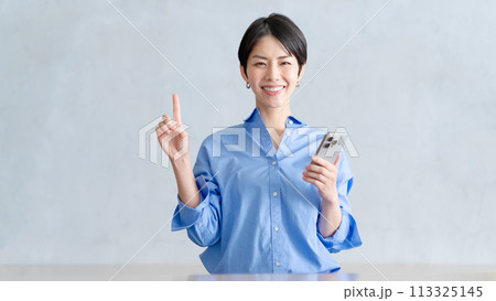 スマホを持って指差しをする女性 113325145