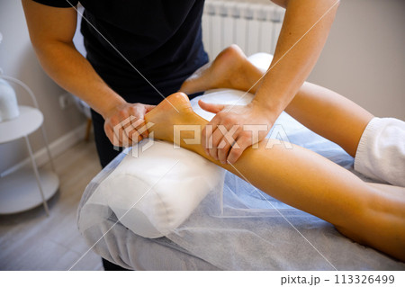 Professional Massage Therapist Working on Lower Body Professional Massage Therapist Working on Lower Body 113326499