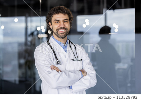 A welcoming Hispanic male doctor with a confident smile, standing in a modern hospital or clinic environment, exuding professionalism and warmth. 113328792