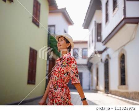 female summer travel to Antalya, Turkey. young asian woman in red dress walk through old town Kalechi , female tourist traveler discover interesting places and popular tourist attraction 113328972