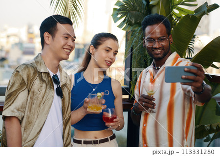 Smiling man taking selfie with best friends at party 113331280